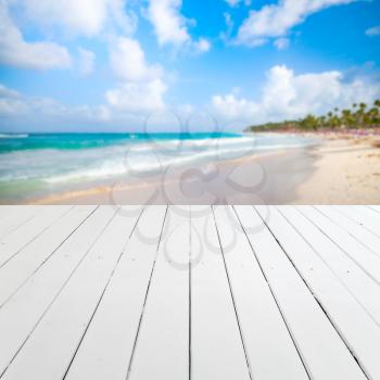 Empty white wooden pier perspective with blurred beach landscape on a background