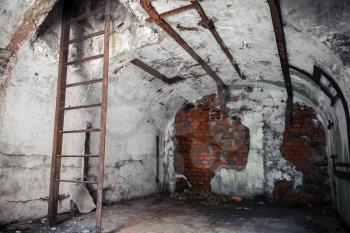 Old empty abandoned bunker interior with white walls and rusted constructions