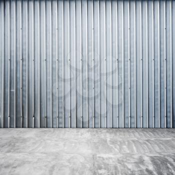 Abstract empty garage interior with ridged metal wall and concrete floor