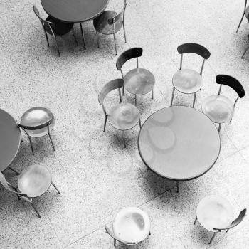 Round tables and chairs stand in empty cafe interior, top view monochrome square photo