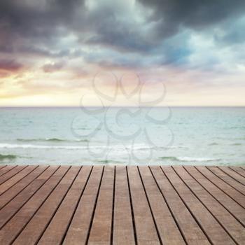 Sea, sand and wooden pier perspective, square photo with selective focus and blurred sky background