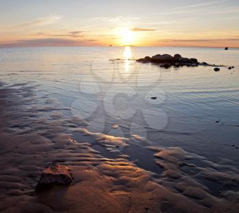 Golden sunset on the Baltic sea. Coastal landscape with setting Sun reflections on the water and sand