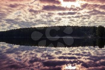 Bright cloudy sky over lake reflects in still water