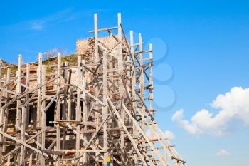 Ancient building is under construction. Wooden scaffolding and blue sky