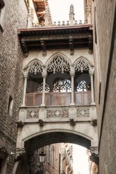Ancient arch and balcony over Carrer del Bisbe, Gothic Quarter, Barcelona. Vertical photo