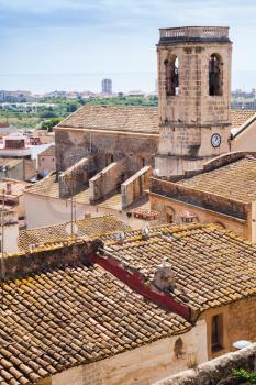 Vertical cityscape of Spanish resort town Calafell in summer. Bell tower and red tiling roofs in old part of town