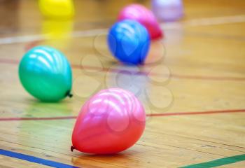 Colorful balloons on wooden floor of sports hall