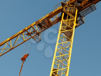 Yellow tower crane fragment above blue sky