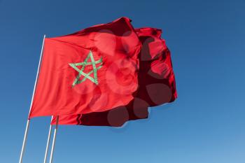 National flags of Morocco above clear blue sky