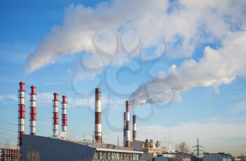 Industrial landscape. Power plant tubes with smoke above blue sky