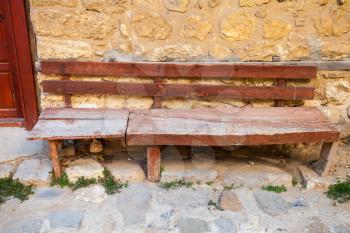 Old red wooden bench near be the stone wall in the old town Nesebar, Bulgaria
