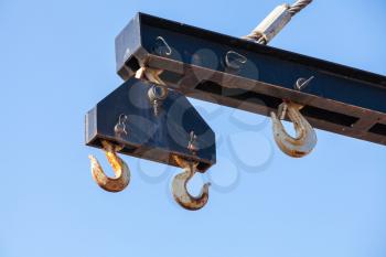 Hooks hanging on beam of harbor crane over blue sky background