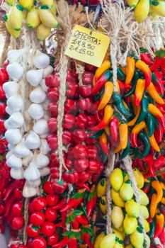 Decorative vegetables and fruits with price label hang on the counter of Italian souvenir shop