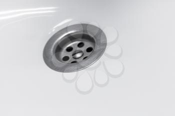 Standard round drain hole in white domestic sink, macro photo with selective focus