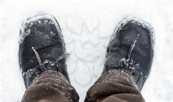 Black leather men's shoes on the feet with snow