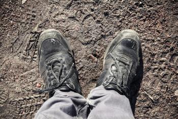 Male feet in dirty shoes standing on road mud