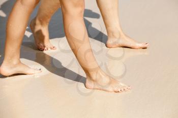 Women legs walk on a wet sandy beach on the sea coast