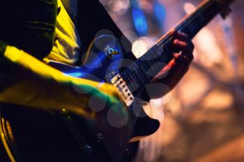 Colorful blurred rock music background, guitar player on a stage with colorful illumination