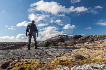 Young man goes on the rock and looks over horizon