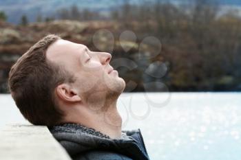 Outdoor Portrait of Young Caucasian man relaxing with closed eyes