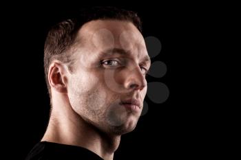 Haughty young Caucasian man's portrait. Close-up face isolated on black