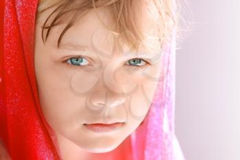 Closeup bright portrait of calm blond Caucasian little girl in red shawl
