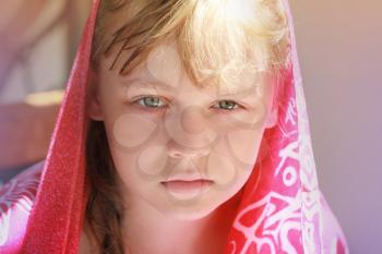 Closeup portrait of calm blond Caucasian little girl in red shawl