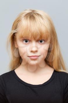 Closeup studio face portrait of little Caucasian ordinary girl isolated on gray background