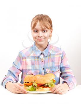 Little smiling blond girl with big homemade hamburgers on white plate