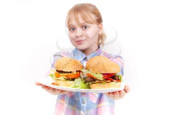 Little smiling blond girl with big homemade hamburgers on white plate