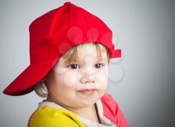 Studio portrait of funny little child in a red baseball cap