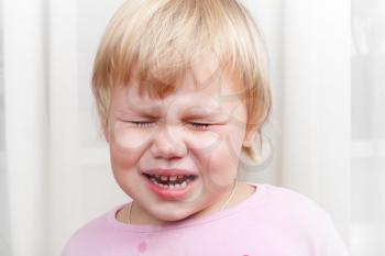 Closeup portrait of blonde crying Caucasian baby girl
