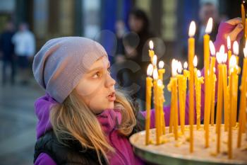 Little blond Caucasian girl with candles in Orthodox Russian Church