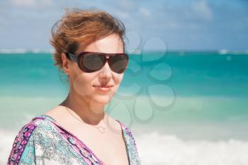 Young beautiful Caucasian woman in sunglasses. Summer outdoor closeup portrait on the ocean coast