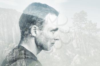 Young adult Caucasian man, profile portrait combined with mountain forest landscape, double exposure photo effect
