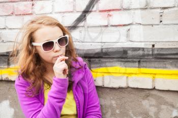 Blond teenage girl with lollipop, vertical urban outdoor portrait