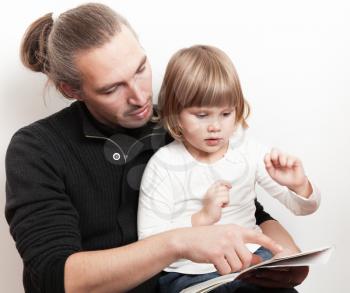 Young man reading book with little Caucasian girl over white wall, studio shoot