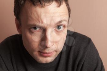Young serious Caucasian man, close-up studio portrait over gray wall background