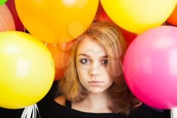 Studio portrait of beautiful teenage Caucasian blond girl with colorful balloons