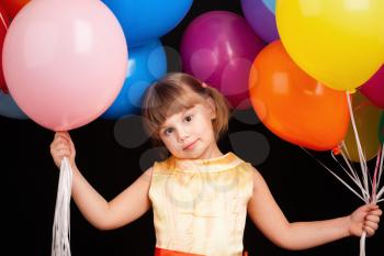 Studio portrait of positive Caucasian blond little girl with colorful balloons