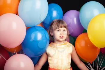 Studio portrait of Caucasian blond little girl with colorful balloons