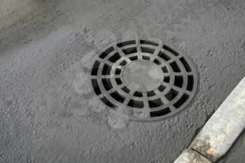 Round drainage sewer manhole cover on urban asphalt road