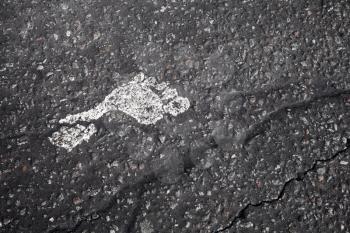 One white footprint on black asphalt pavement