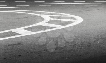 Abstract transportation background. White bent lines over dark asphalt, road marking. Selective focus with shallow DOF