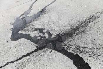 Abstract shaped dark water splash on dry gray urban asphalt pavement