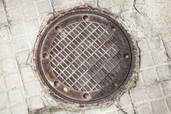 Round rusted hatch in urban pavement, sewer manhole cover