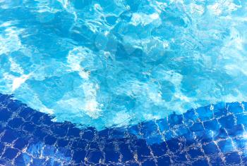 Pool water ripple background texture with bright reflections and blue tiles.