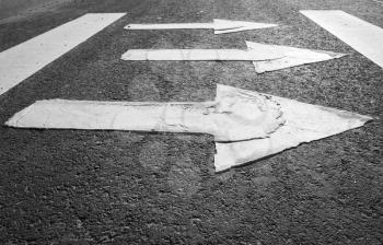 White arrows over black highway asphalt, pedestrian crossing road marking fragment
