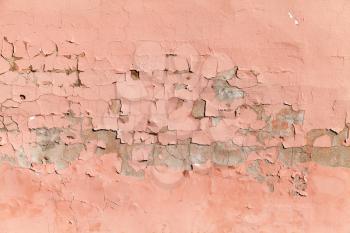 Background texture of an old concrete wall with peeling layer of pink paint