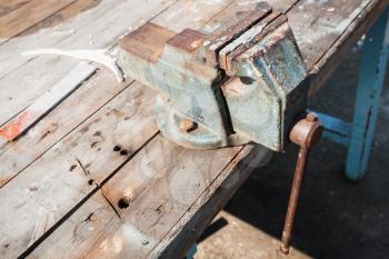 Old vice mounted on a workbench, closeup photo with selective focus